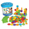 Blue storage bucket next to colorful plastic gear pieces, green base plates, and assembled structures.