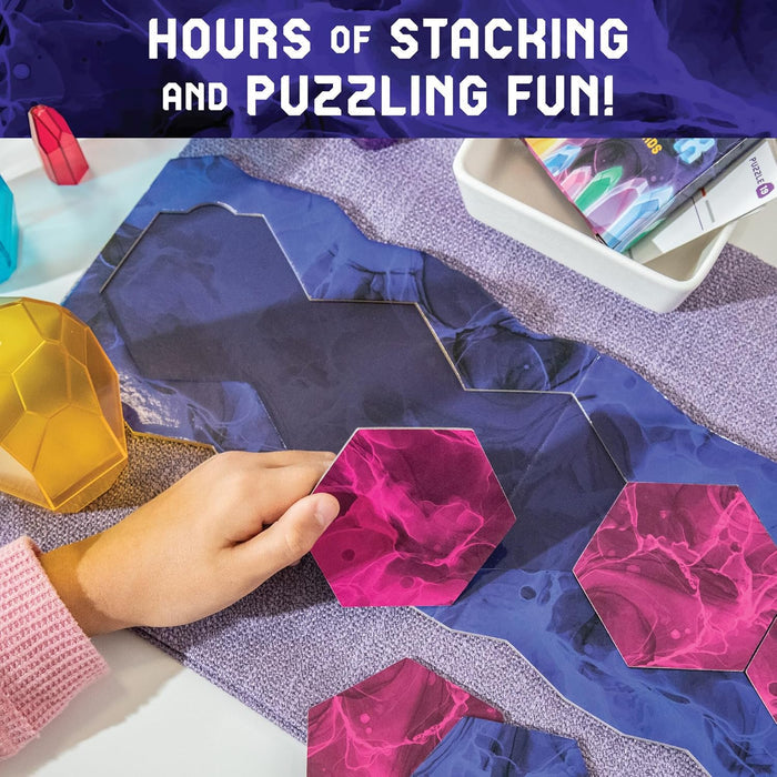 A hand places pink hexagonal tiles onto a blue marbled game board next to translucent yellow and red crystal pieces.