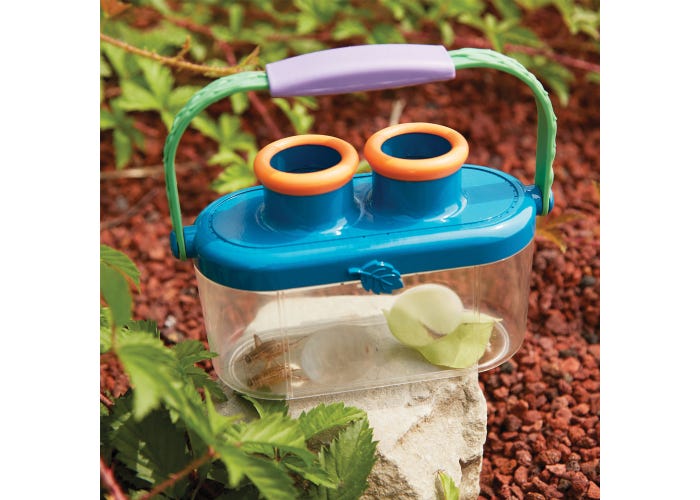 Blue and clear bug viewer with two orange magnifying lenses and a green handle, containing a cricket and leaves.