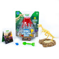 Dinosaur dig kit with volcano packaging, assembled T-Rex skeleton, sand base, green tool, blue gem, and fact card.
