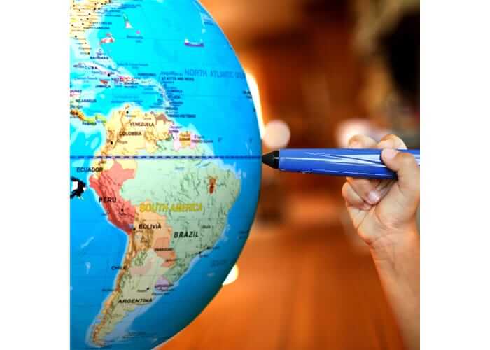 Close-up of a blue talking globe showing South America being touched by a blue stylus held by a child's hand.