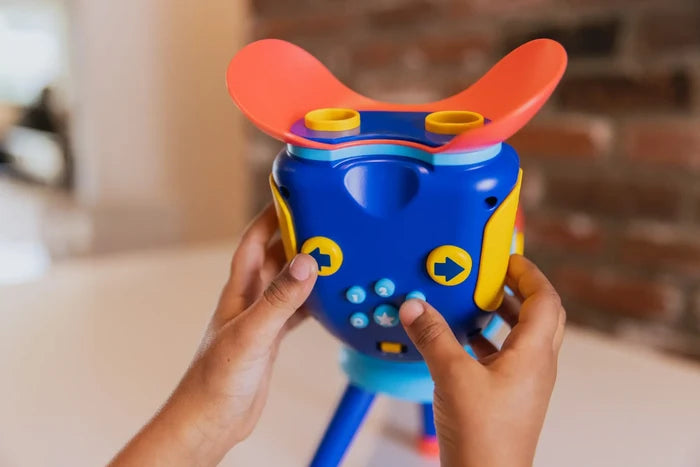 Child's hands holding a blue and yellow toy viewer with an orange visor and light blue control buttons.