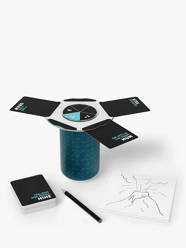 Blue patterned game cylinder with a top spinner, action cards, pencil, and a volcano sketch on a white notepad.