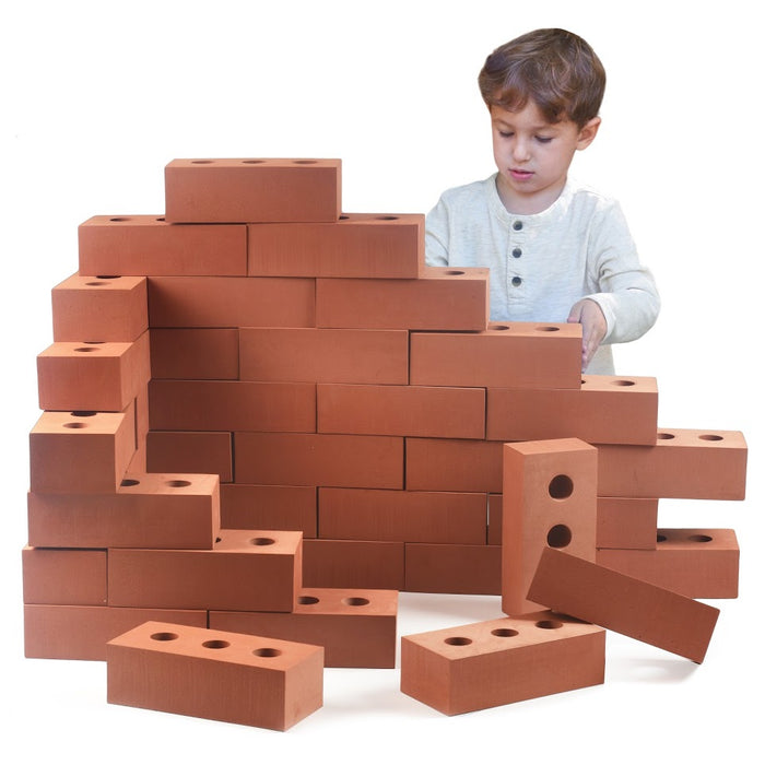 A child building a wall using large, terracotta-colored toy bricks with circular holes on a white background.