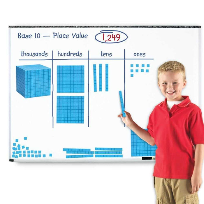 Boy in a red shirt uses blue magnetic base ten blocks on a whiteboard chart to represent the number 1,249.
