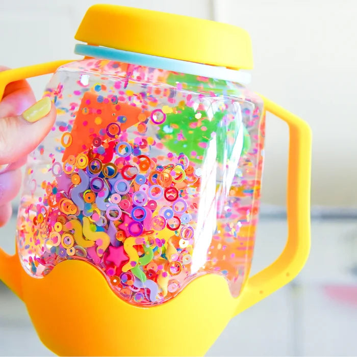 Yellow sensory jar filled with colorful plastic shapes like stars and rings floating in clear liquid.
