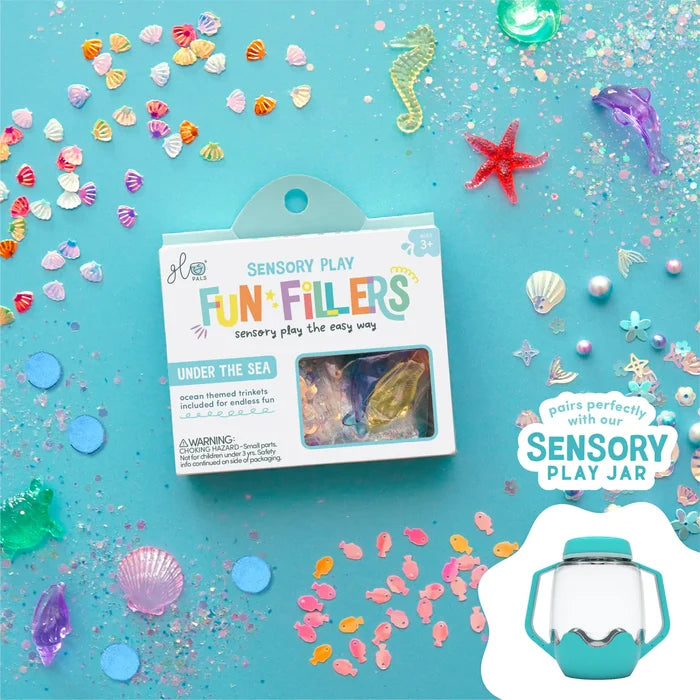 Under the Sea sensory kit box surrounded by colorful plastic shells, fish, and glitter on a bright blue background.