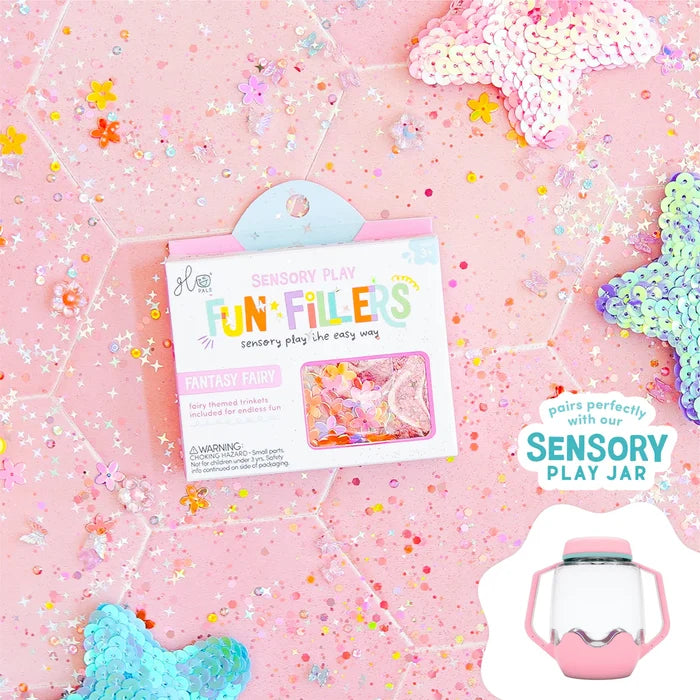 Fantasy Fairy sensory play filler box surrounded by colorful sequins and stars on a pink surface.