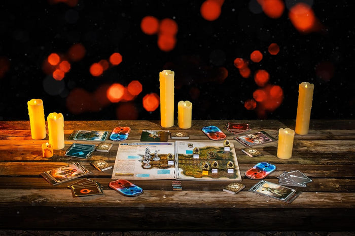 Tabletop fantasy game components, cards, and miniatures on a rustic wooden table lit by glowing candles.