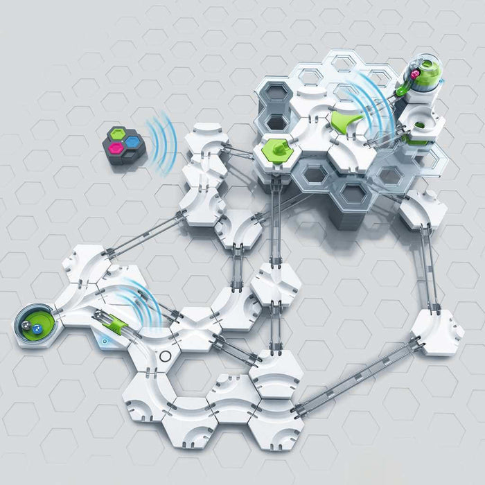 Complex white and gray marble run with green electronic launchers and a handheld remote control on a hexagonal grid.