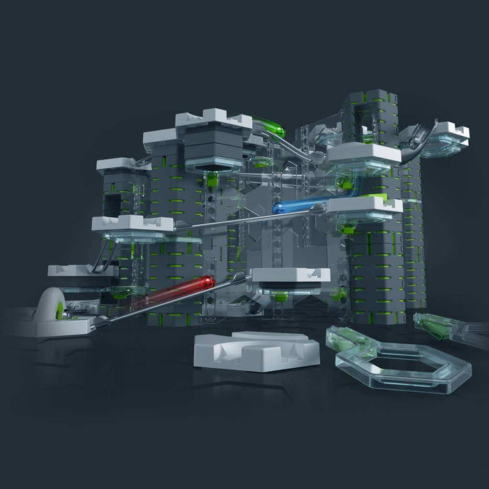 Vertical marble run with tall grey towers, green accents, white hexagonal platforms, and a red ball on a clear track.