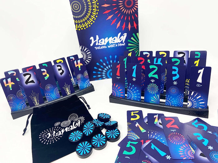 Colorful firework-themed cards in black racks, blue tokens, and a velvet bag for the Hanabi Deluxe board game.