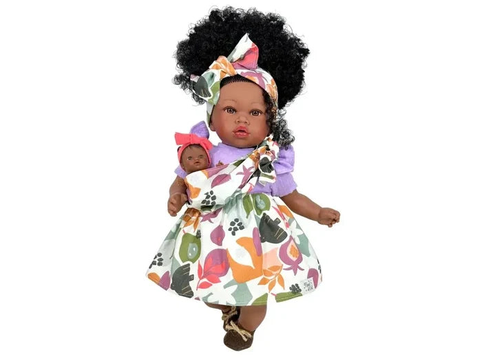 Black doll with a large afro, colorful floral dress, and headband, carrying a small baby doll in a matching sling.
