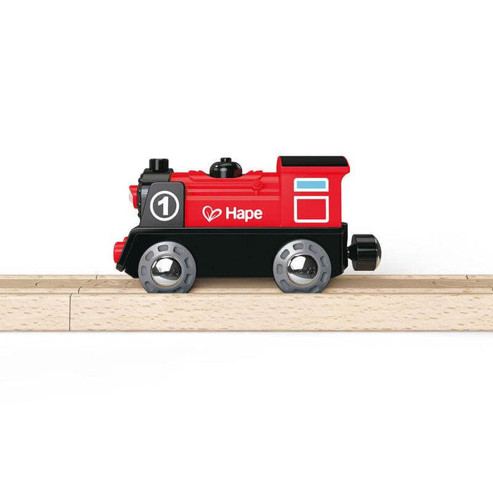 Red and black toy train engine with number 1 and the Hape logo, shown on a light wooden track.