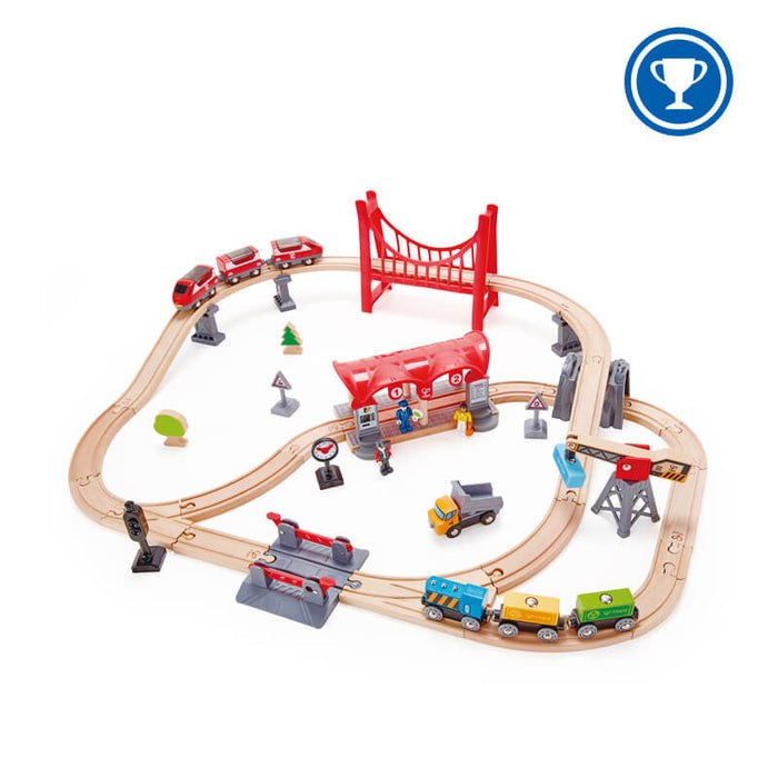 Wooden railway loop featuring a red bridge, station, crane, and colorful freight and passenger trains.