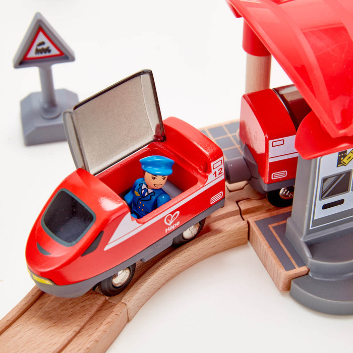 Red toy train with a conductor figurine in an open cockpit, sitting on a curved wooden track.