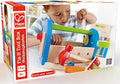 Hape toy packaging shows a child with a blue and wood tool kit featuring a red hammer, green handle, and wooden wrench.