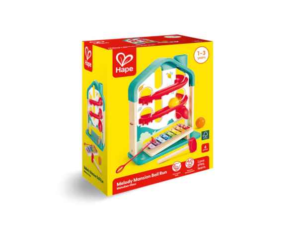 Yellow box showing a house-shaped toy with teal frame, red ball tracks, a multi-colored xylophone, and a mallet.
