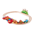 Oval wooden train track with colorful animal cars, a rainbow xylophone bridge, and three monkeys on a green hill.