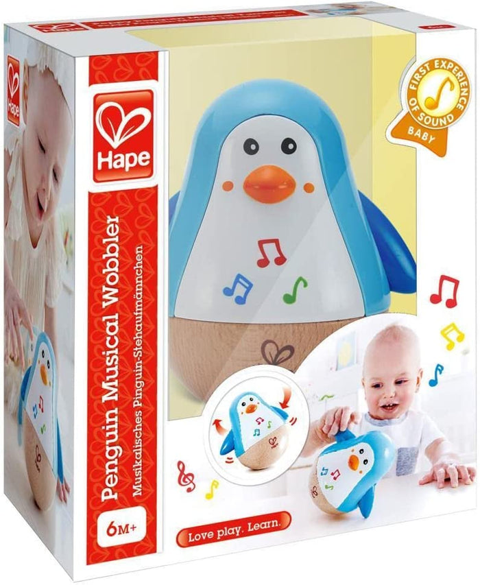 Blue and white penguin toy with wooden base and musical notes in packaging showing a baby playing.