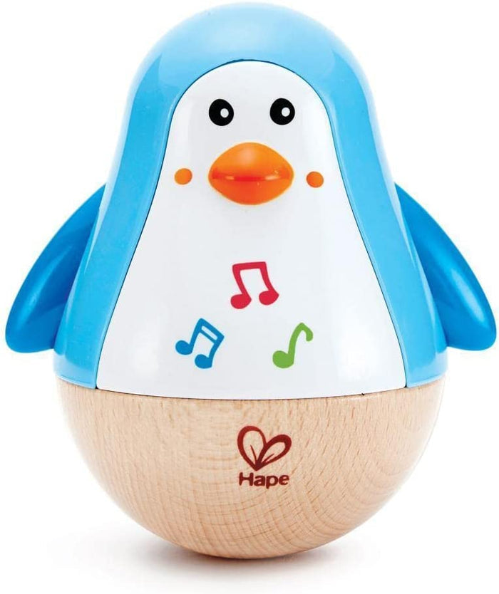 Blue and white penguin toy with a rounded wooden base, orange beak, and three colorful musical note icons.
