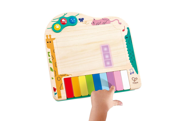 Hape wooden toy piano with rainbow keys, animal illustrations, and pixel display being played by a child's hand.