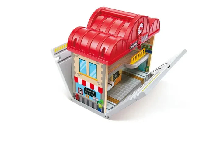 Red-roofed toy station with fold-out track ramps, featuring a coffee shop facade and interior platform.