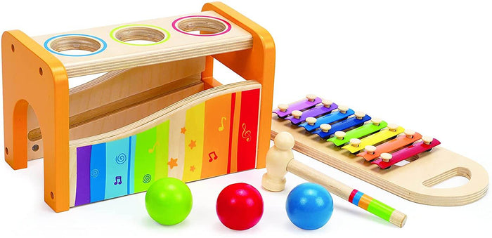 Wooden toy bench with three ball holes, green, red, and blue balls, a mallet, and a sliding rainbow xylophone.