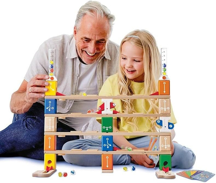 Grandfather and girl playing with a multi-level wooden marble run featuring colorful blocks, tracks, and marbles.