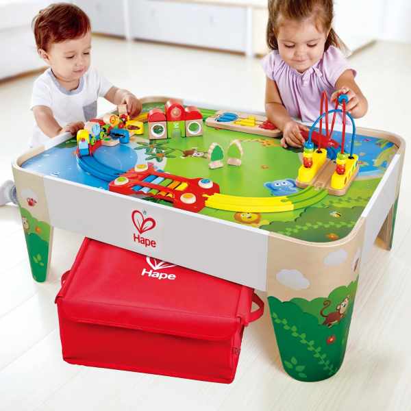 Wooden Hape activity table with jungle scenes, colorful train tracks, bead maze, and a large red storage bin underneath.