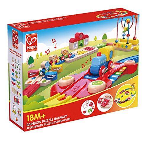 Red Hape box showing a wooden toy train on colorful musical tracks with a xylophone, bead maze, and bright blocks.