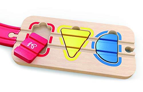 Wooden train track shape sorter with red, yellow, and blue blocks fitting into matching color-outlined cutouts.