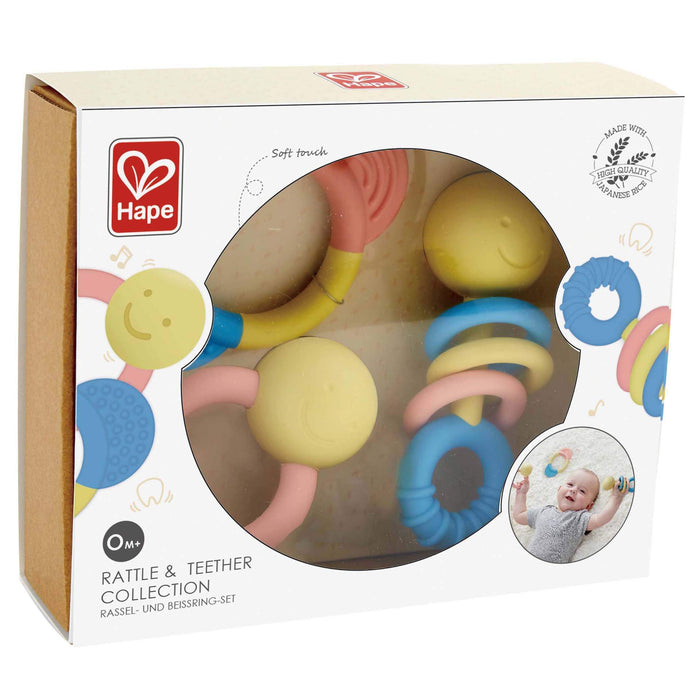 Three pastel-colored baby rattles and teethers with smiley faces in a white Hape display box.