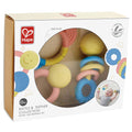 Three pastel-colored baby rattles and teethers with smiley faces in a white Hape display box.