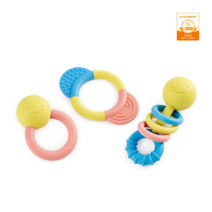 Set of three pastel yellow, blue, and pink baby rattles and teethers featuring smiley faces and textured surfaces.
