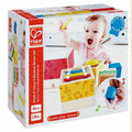 Box for wooden musical blocks showing a toddler playing with colorful xylophone, drum, and shaker-themed stacking cubes.