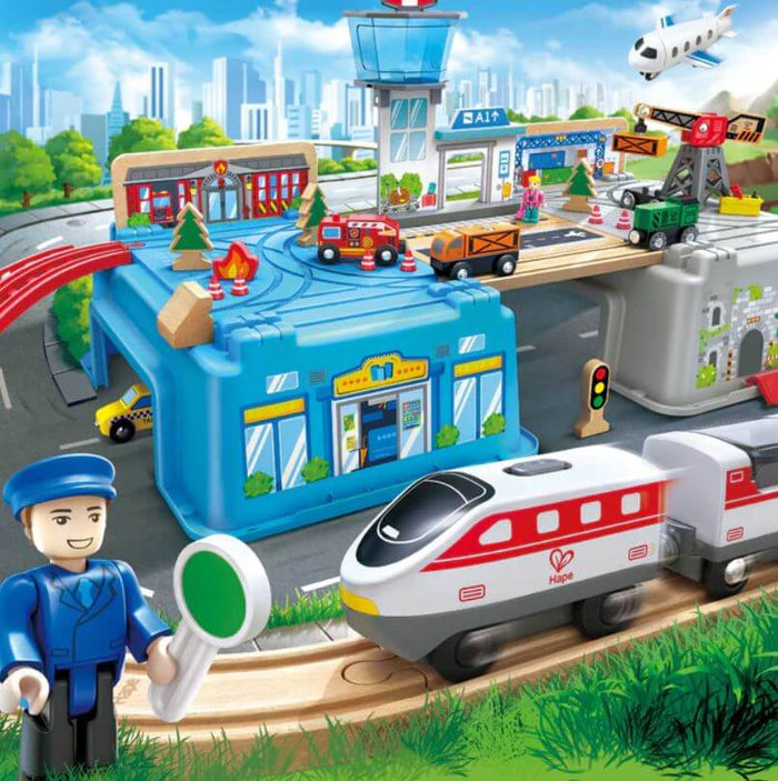 Multi-level wooden train set featuring a blue bucket base, white bullet train, airport tower, and fire station toy.