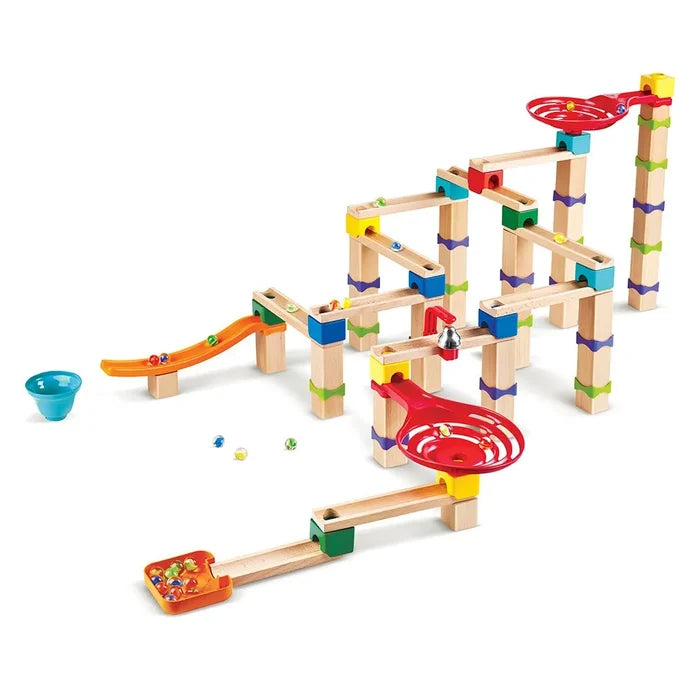 Wooden marble track with tall towers, red spiral funnels, colorful blocks, orange ramps, a bell, and glass marbles.