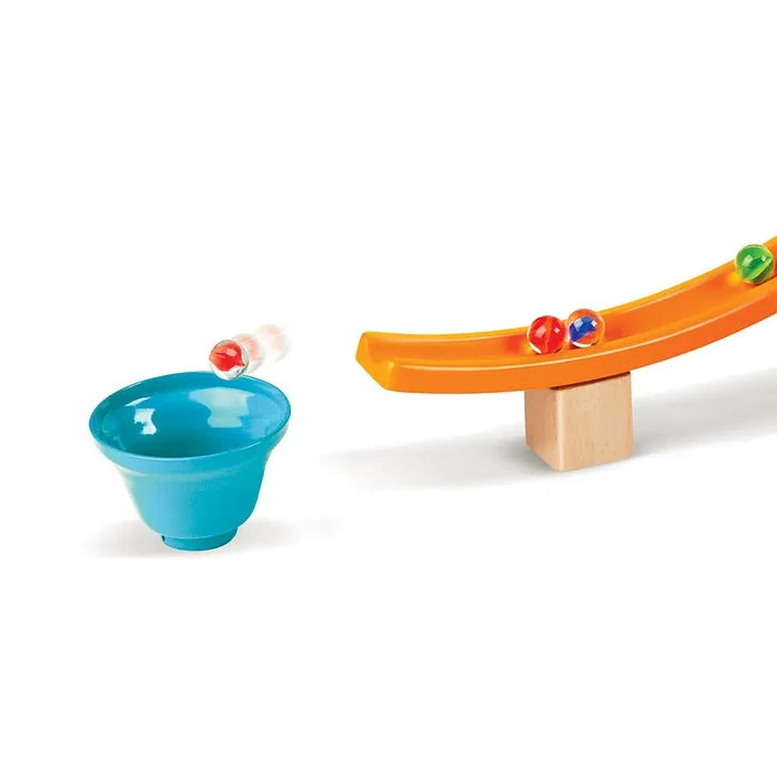 Marble jumping from a curved orange track into a blue funnel, with colorful marbles and wooden support block.