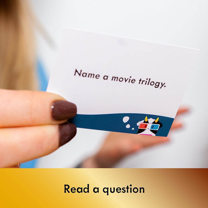Hand holding a white card reading Name a movie trilogy with a cartoon cow wearing 3D glasses on a blue banner.