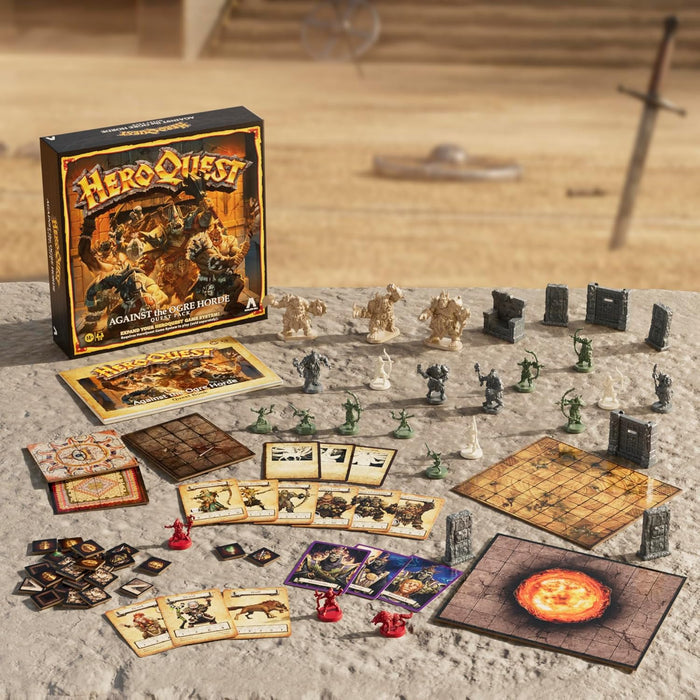 HeroQuest box and contents: grey and green miniatures, colorful cards, and map tiles on a rocky stone surface.