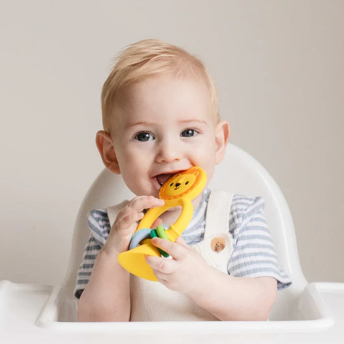 Baby in a high chair chewing on a yellow silicone lion toy featuring colorful sliding rings and a suction cup base.