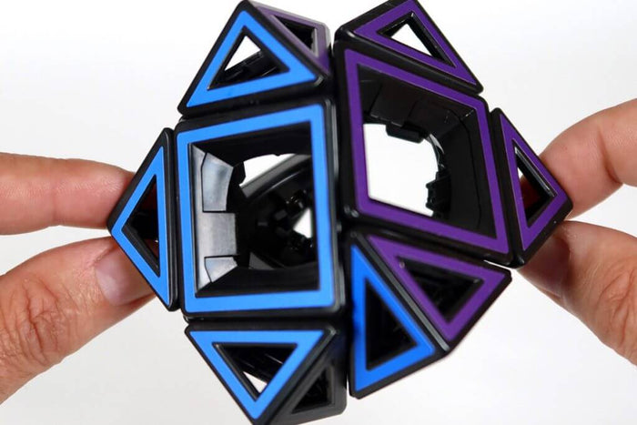 Hollow black skewb puzzle cube with blue and purple outlines, held by hands to show its open, empty interior.