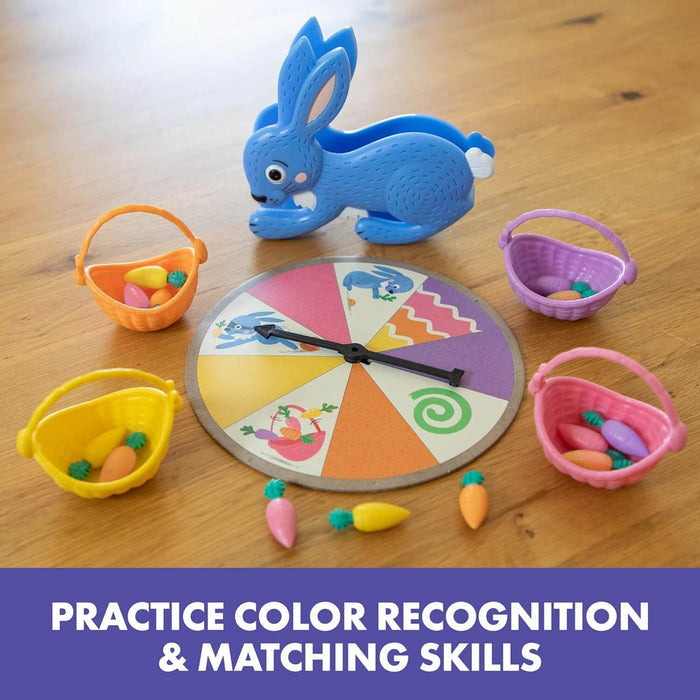 Blue bunny squeezer, game spinner, and four colorful baskets with small plastic carrots on a wooden surface.
