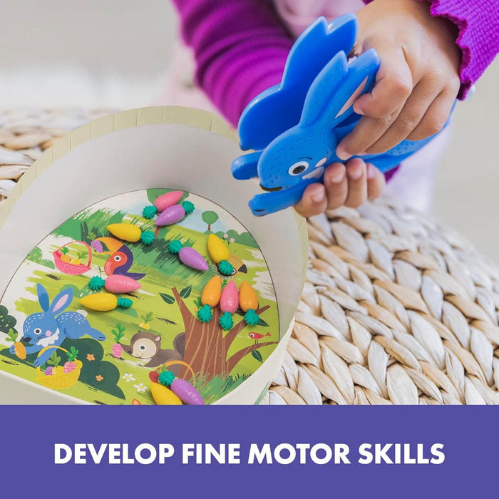 Child using blue bunny squeezer to grab colorful carrots from a game board. Text: DEVELOP FINE MOTOR SKILLS.
