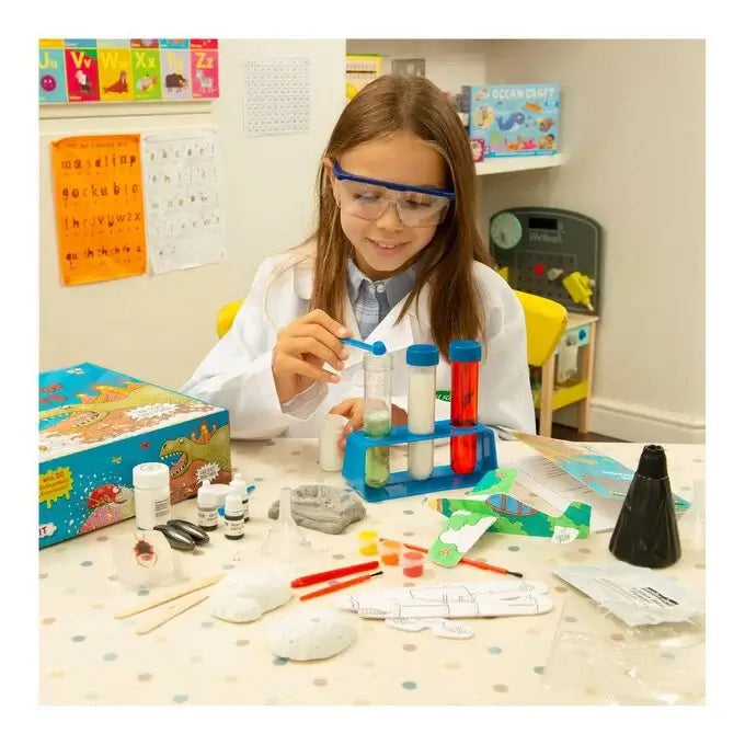 Girl in lab coat and goggles conducts experiments with colorful test tubes, a volcano model, and science kit tools.