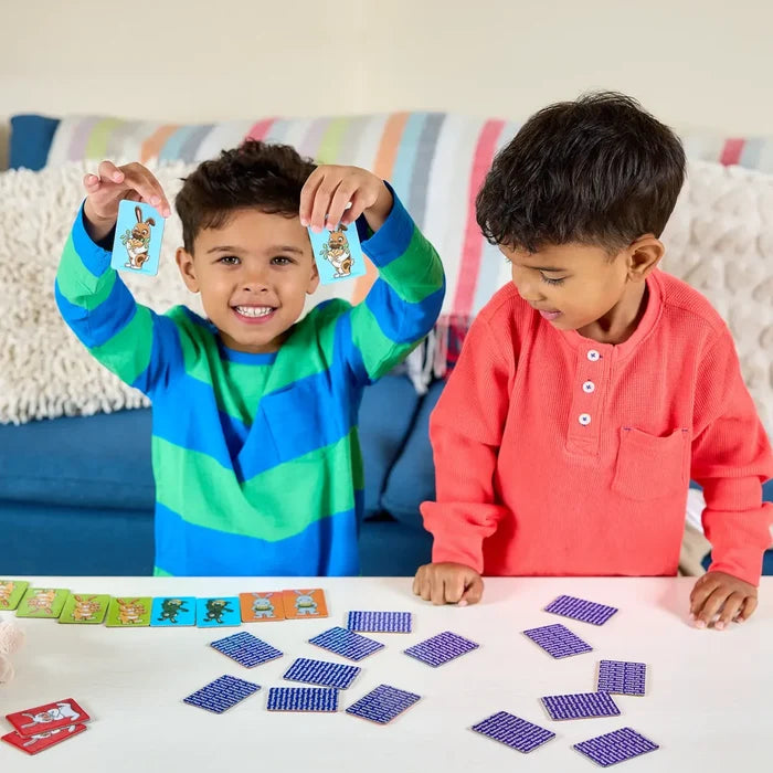 Two boys play a bunny matching game on a white table with colorful rabbit cards and purple patterned tiles.