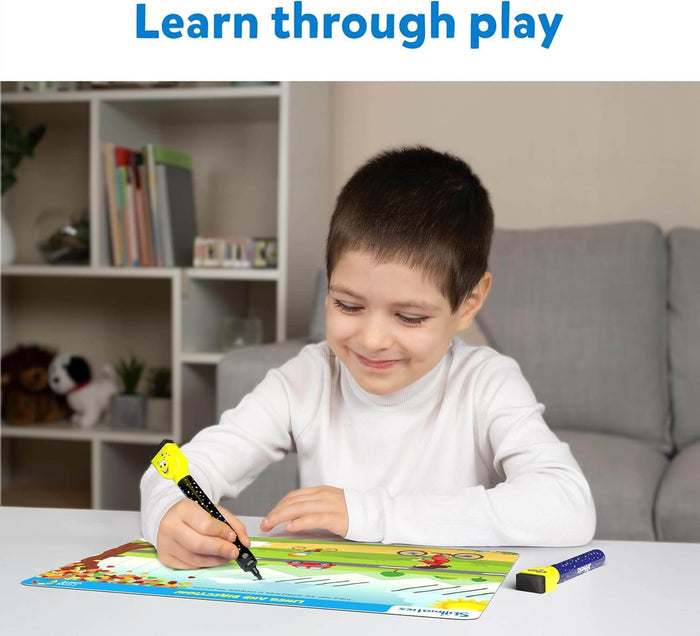 Smiling boy tracing lines on a colorful landscape dry-erase mat using a yellow and black marker.