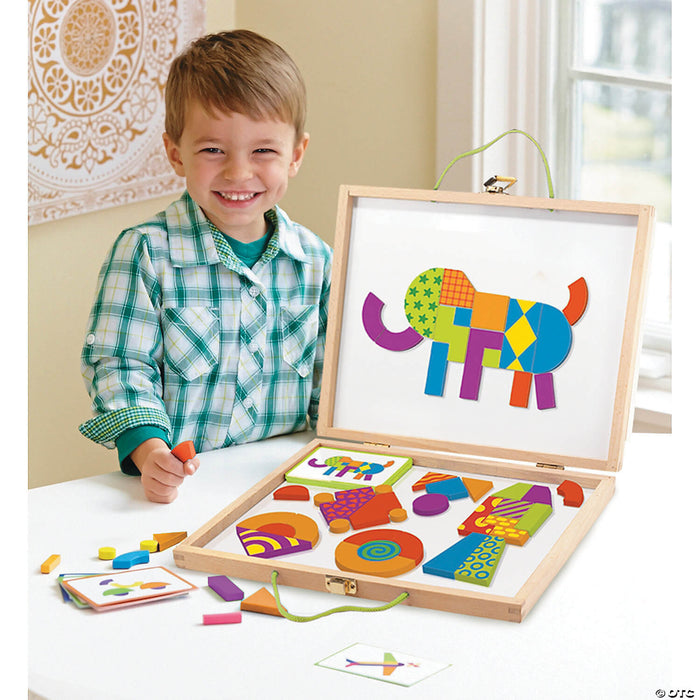 Smiling boy with wooden case of colorful patterned magnetic tiles arranged to form an elephant on a whiteboard.