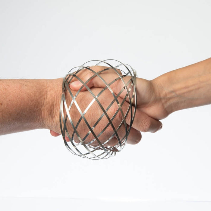 Silver metallic mesh sphere made of intersecting bands surrounding two hands shaking on a white background.